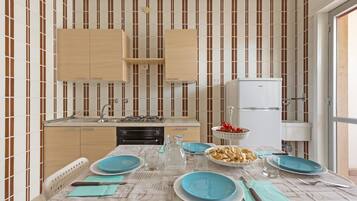 A compact kitchen with striped wallpaper, wooden cabinets, a gas stove, and a white refrigerator.