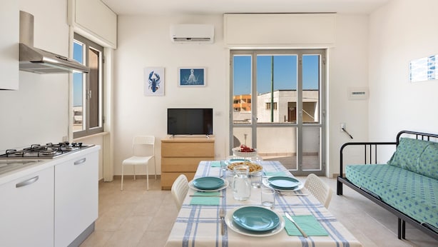 Un espacio habitable compacto con kitchenette, comedor y cama.