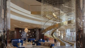 A spacious lobby with a grand staircase, plush seating, and a chandelier. - Paramount Hotel Dubai (Dubai)