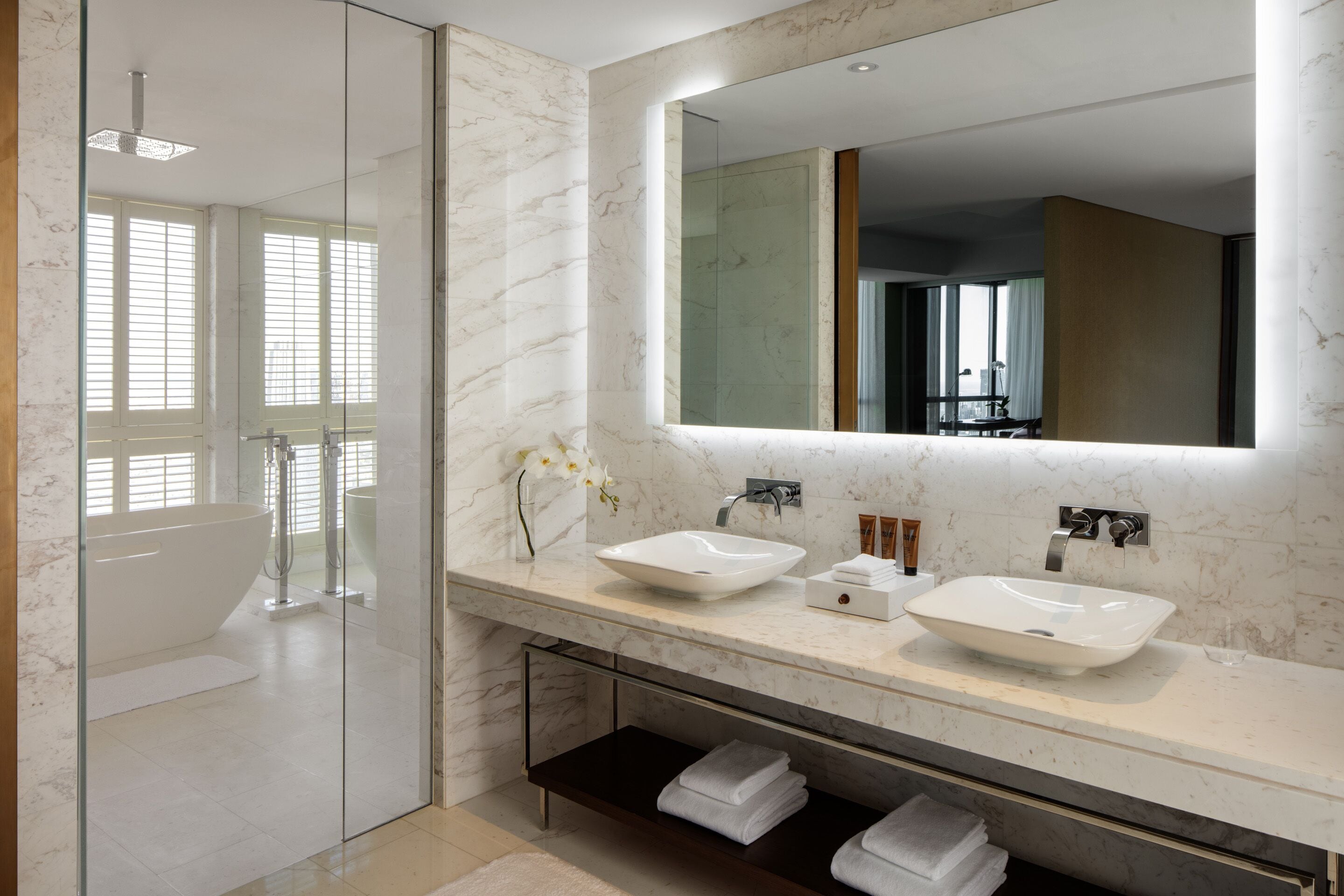 A modern bathroom with two sinks, a large mirror, and a glass-enclosed shower.