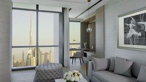 A modern living room with a large window offering a city view, a tufted ottoman, a sofa, and a framed artwork on the wall. - Paramount Hotel Dubai (Dubai)