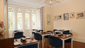 A dining area with tables and chairs, a chandelier, and framed artwork on the wall. - The Cordelia (Scarborough)