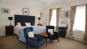 Ein Schlafzimmer mit einem Bett, zwei Sesseln, einem kleinen Tisch, einem Nachttisch, einem Schreibtisch und einem Spiegel.
