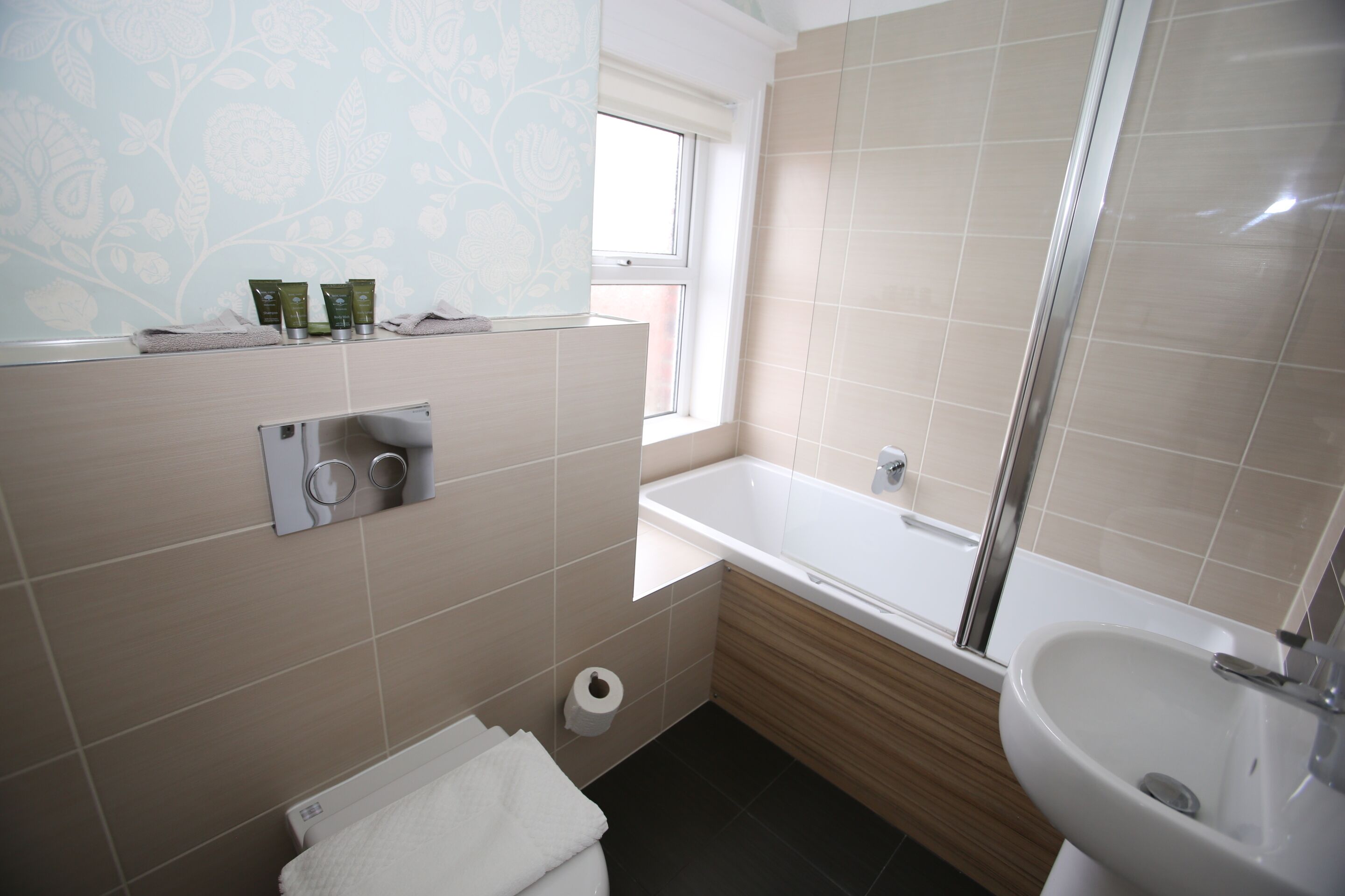 A bathroom with a bathtub, a sink, a toilet, and a window.