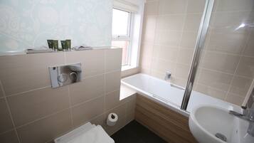 A bathroom with a bathtub, a sink, a toilet, and a window.