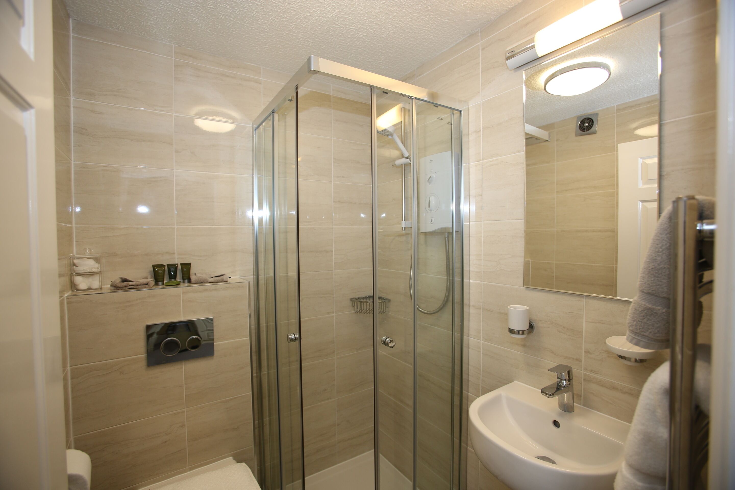 A modern bathroom with a glass-enclosed shower, a sink, and a mirror.