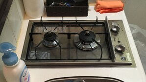 Eine Küche mit einer Edelstahl-Spüle, einem Gasherd und einer Handseifenflasche.