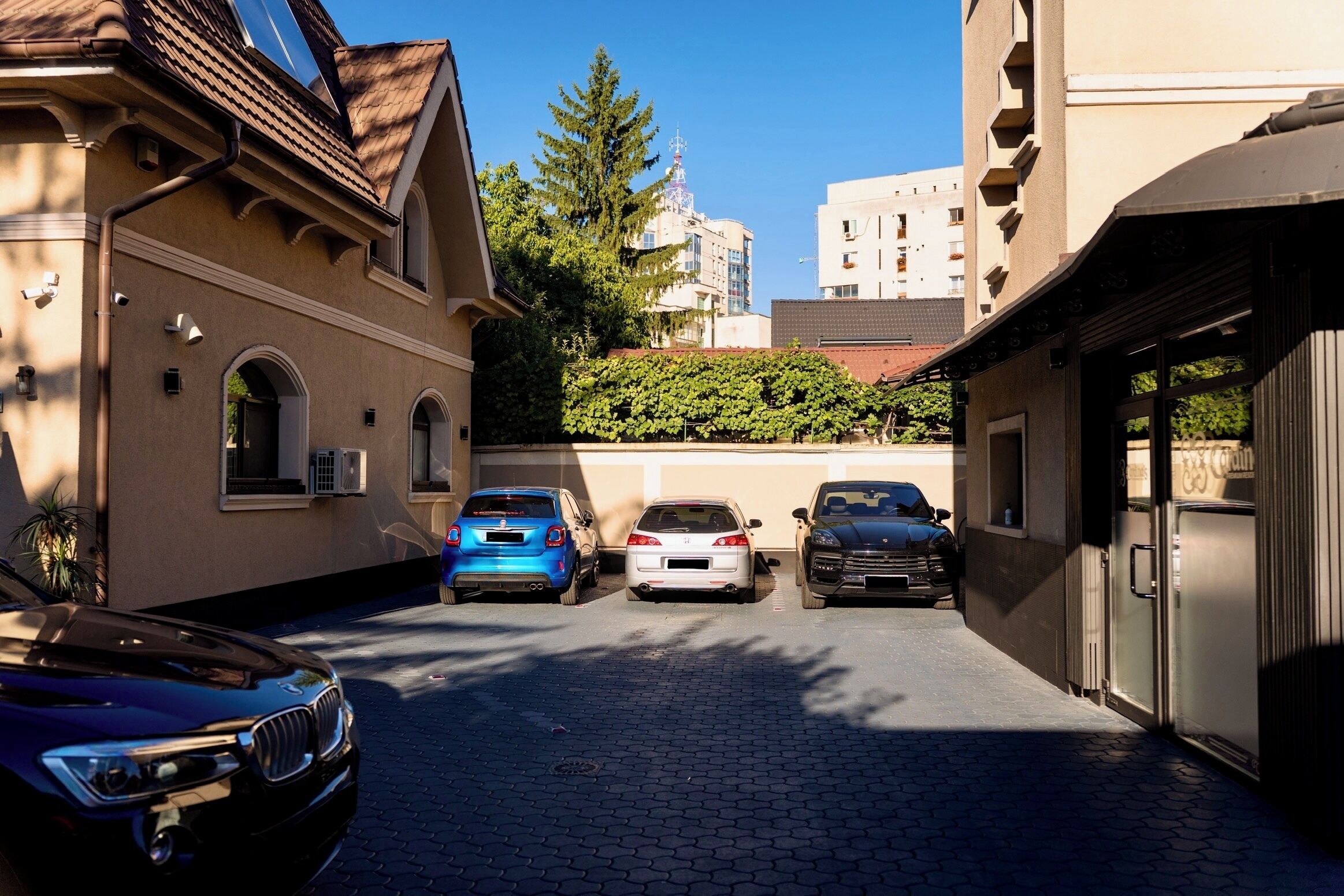 A narrow street with parked cars and buildings on either side.