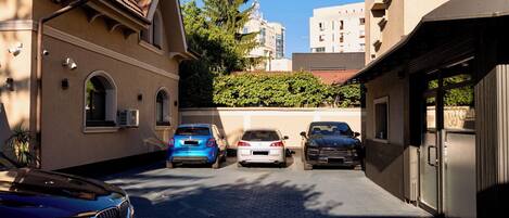 A narrow street with parked cars and buildings on either side.