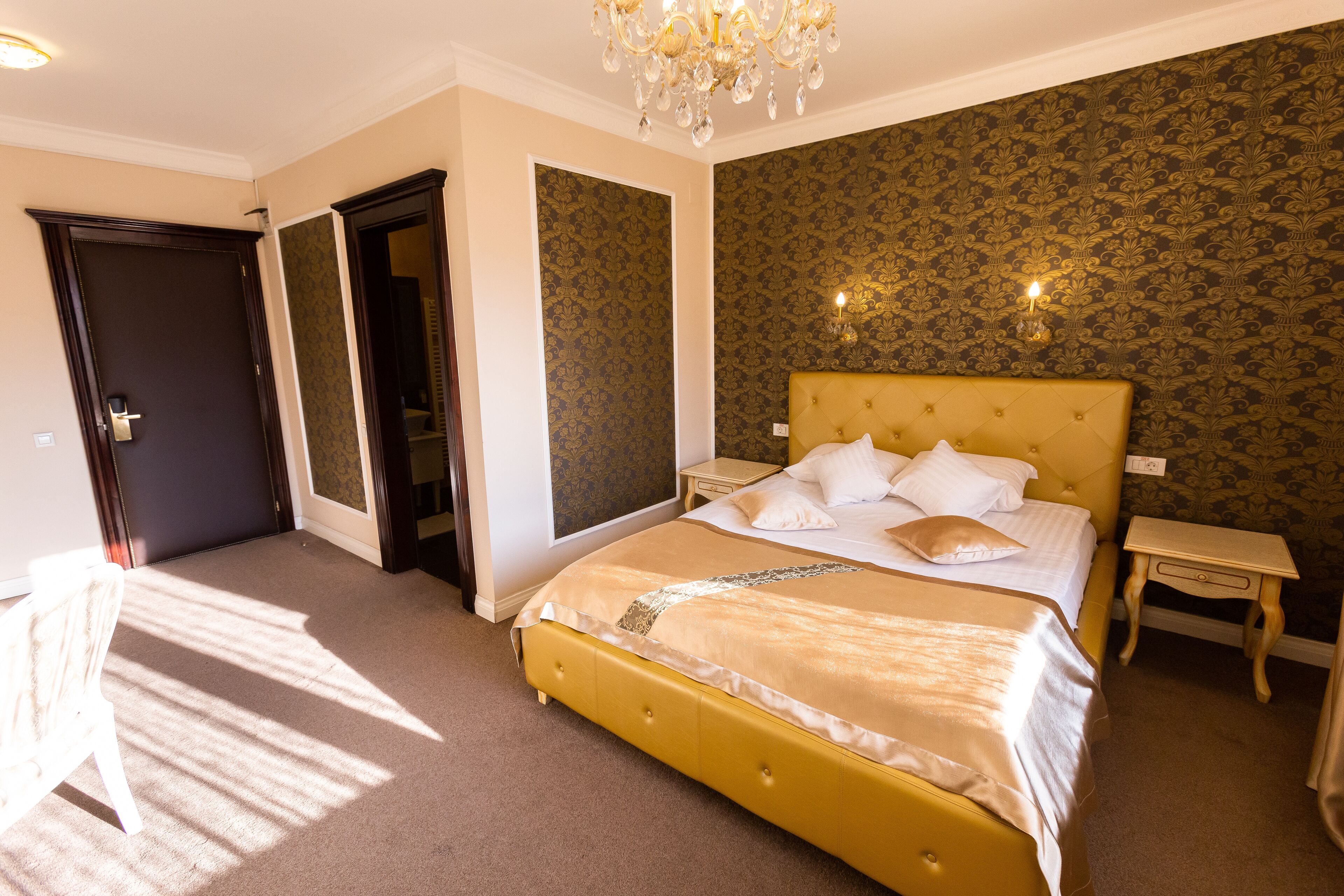 A well-lit bedroom with a large bed, a nightstand, and a chair.