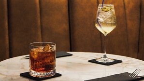 Una mesa con dos bebidas, un menú y un cuadro en la pared.