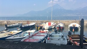 A harbor with various boats docked, a clear sky, and a mountain in the background. - Apartment in a residence on the shores of Lake Garda (Pai)