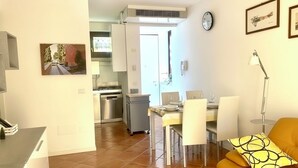 A modern kitchen with a dining area, a sofa, and a clock on the wall. - Apartment in a residence on the shores of Lake Garda (Pai)