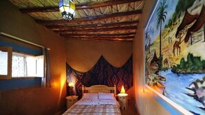Una habitación con una cama, una mesita de noche, un tapiz en la pared y un mural.