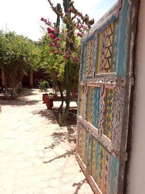 A courtyard with a patterned gate, potted plants, and a cactus. - Maison Nomades (Asrir)