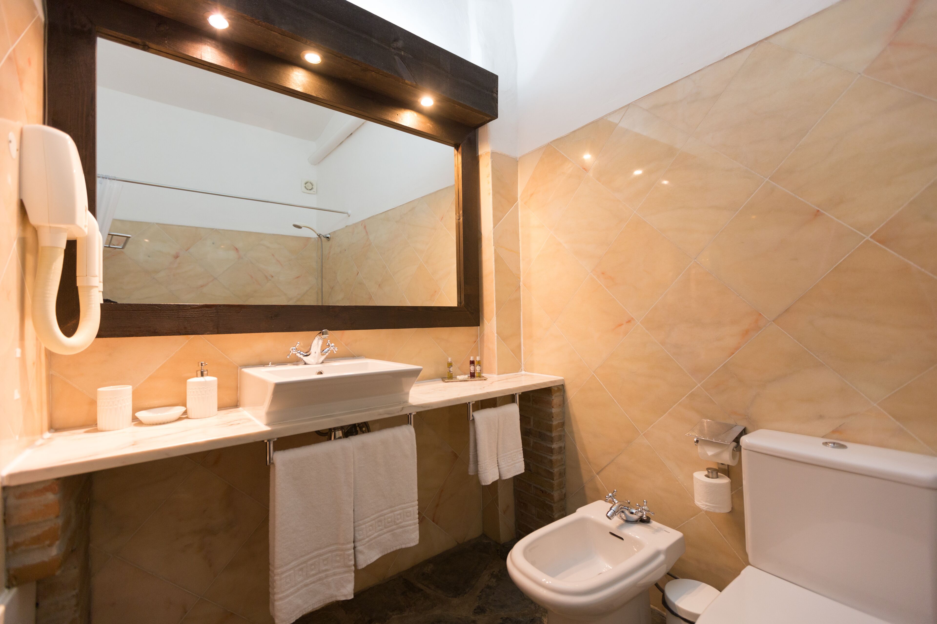 Un baño moderno con un espejo grande, un lavabo, un bidé y un inodoro.