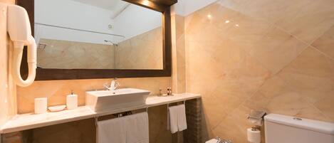 Un baño moderno con un espejo grande, un lavabo, un bidé y un inodoro.