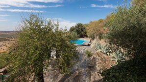 A stone pathway leading to a pool surrounded by greenery and hills.
