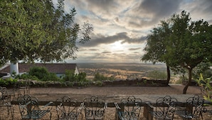 A terrace with metal chairs and a view of a valley.