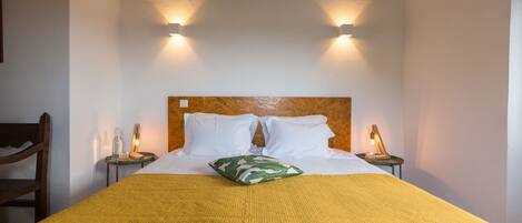 A neatly made bed with a wooden headboard, two bedside lamps, and a green patterned pillow.