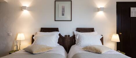 A double bed with two nightstands, each with a lamp, in a room with a framed picture on the wall and a door to the right.