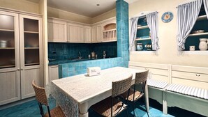 Una cucina con tavolo e sedie, pensili e un rivestimento a parete in piastrelle blu.