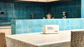 Un piano di lavoro in cucina con un cartello di benvenuto, una piccola pentola e una figura decorativa.