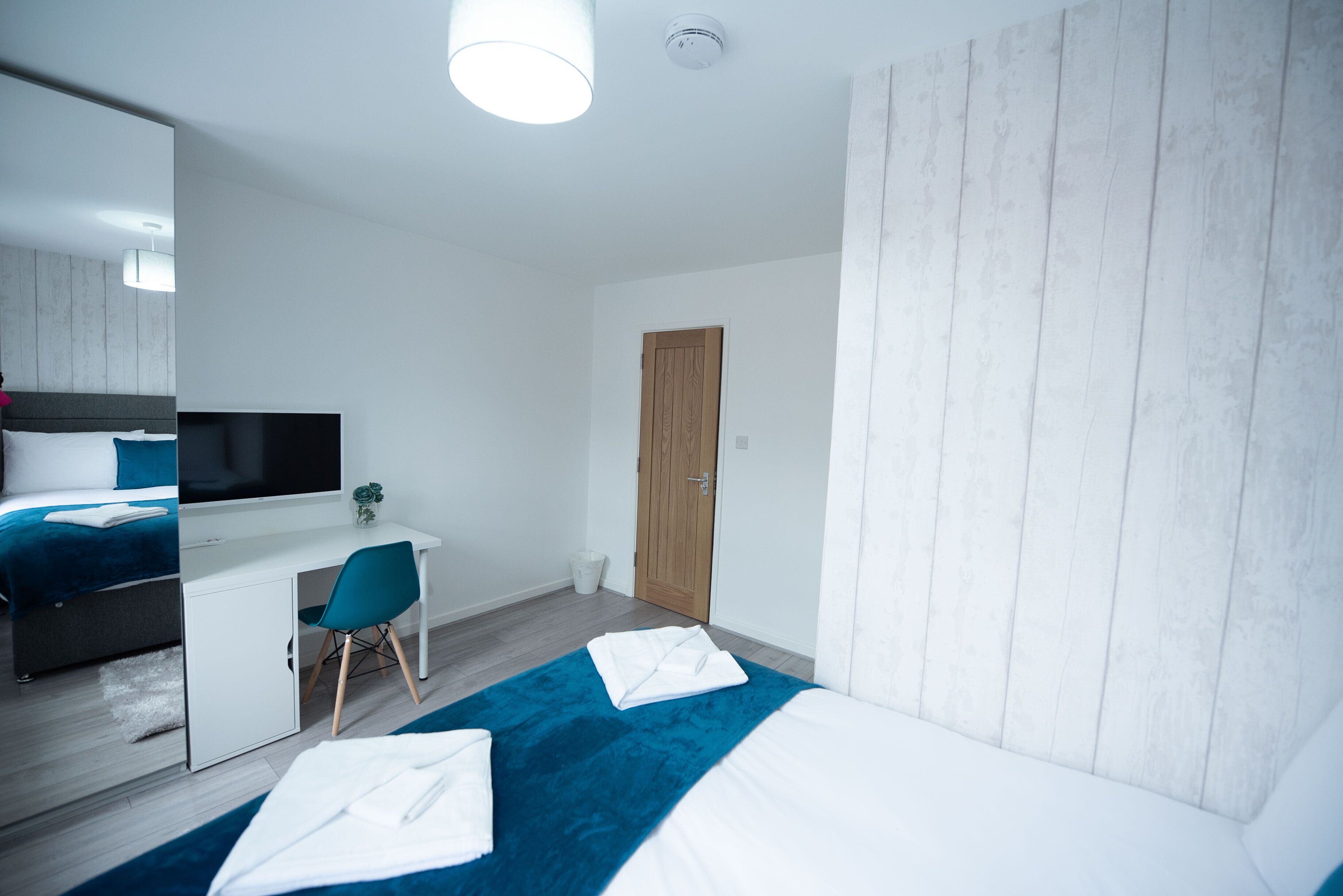 Habitación de hotel moderna con cama, escritorio, silla, televisor y armario.