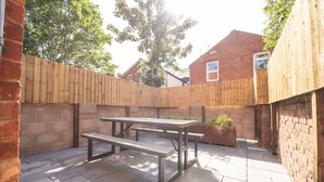 Un patio con cerca de madera, una mesa de picnic y una jardinera.