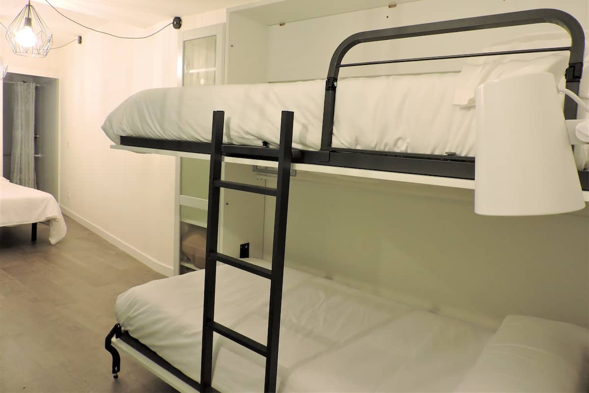 A bunk bed room with a ladder, a door, and a light fixture.
