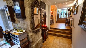 A hallway with a stone wall, a wooden staircase, and a kitchen area with a sink and countertop. - Hotel Jacobeo (Burgos)