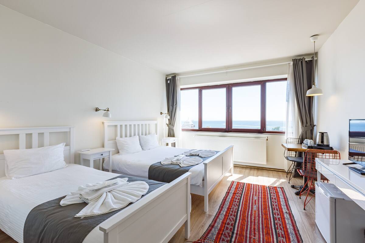 Habitación de hotel con dos camas, un escritorio, un televisor y vistas al mar.