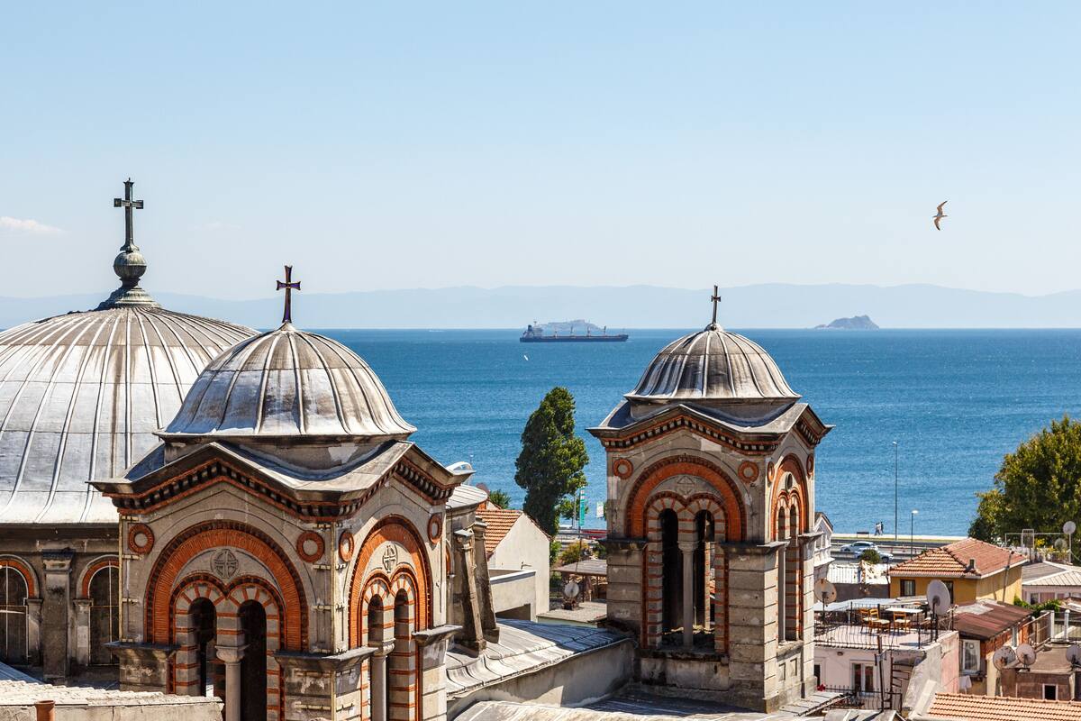 Vista costera con edificios de cúpulas y un barco a lo lejos.