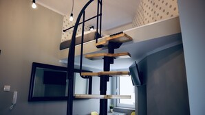 A multi-level room with a bunk bed, a desk, and a television. - GOLDA apartments (Lodz)
