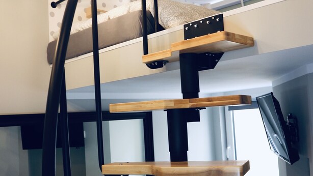 A multi-level bunk bed with a ladder, wooden shelves, and a small table. - GOLDA apartments (Lodz)