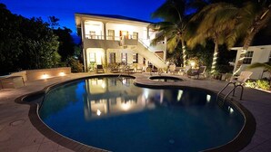 Une piscine entourée d’une terrasse, de palmiers et d’un bâtiment doté d’un escalier.