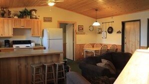 A cozy kitchen with wooden cabinets, a refrigerator, and a dining area with a table and chairs. - Viking Bay Resort & Lodge (Miltona)