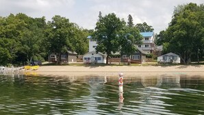 A lakeside property with a swimming area, a sandy beach, and several houses with balconies. - Viking Bay Resort & Lodge (Miltona)