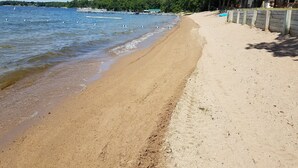 A beach with a wooden fence, a clear sky, and a forested hill in the background. - Viking Bay Resort & Lodge (Miltona)