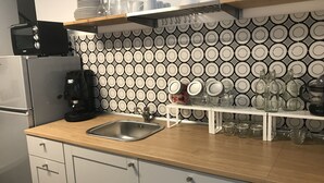 A modern kitchen with a stainless steel sink, a coffee maker, and a microwave. There are shelves above the counter holding plates, glasses, and jars. - B&B BaRock (Noto)