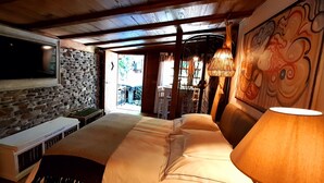 A cozy room with a stone wall, a TV mounted above a fireplace, a sofa with a lamp, and a mural on the wall. - Cottage and Chalet Pr Klemuc (Bled)