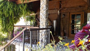 A rustic wooden cabin with a stone pillar, a deer skull mounted on the wall, and a wooden staircase leading to a porch. - Cottage and Chalet Pr Klemuc (Bled)