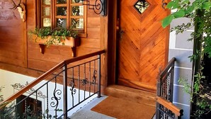 A wooden cabin with a wooden door, a stone staircase, and a metal railing. - Cottage and Chalet Pr Klemuc (Bled)