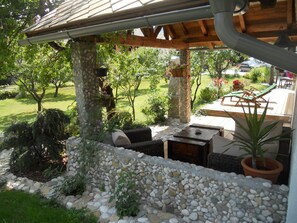 A covered outdoor seating area with stone walls, a pergola, and a view of a garden. - Cottage and Chalet Pr Klemuc (Bled)