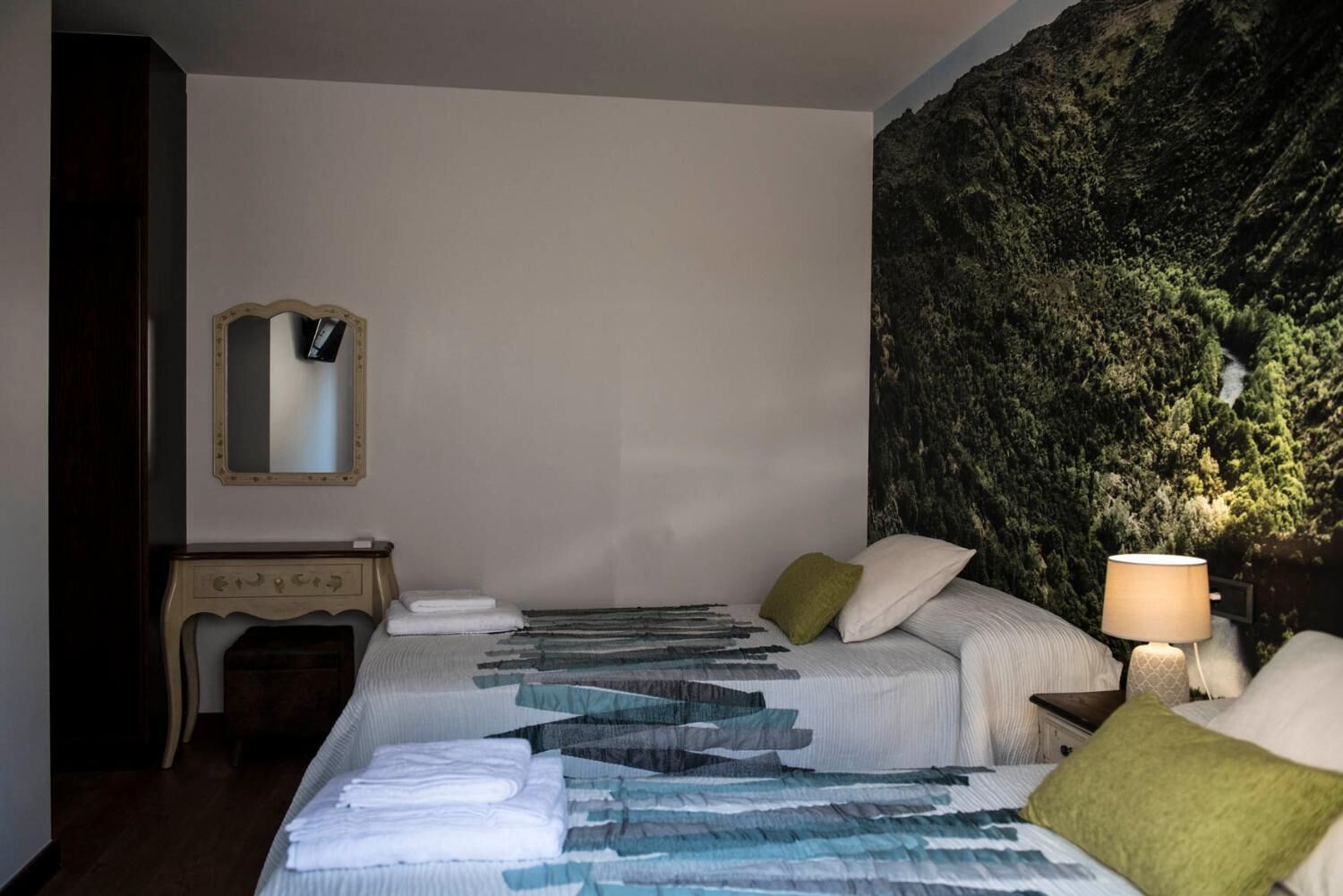 A hotel room with a bed, a nightstand, a mirror, and a wall with a textured design.