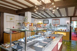 Un buffet avec différents plats présentés dans des récipients et un saladier rempli de fruits.