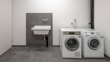 A laundry area with two front-loading washing machines and a wall-mounted sink.