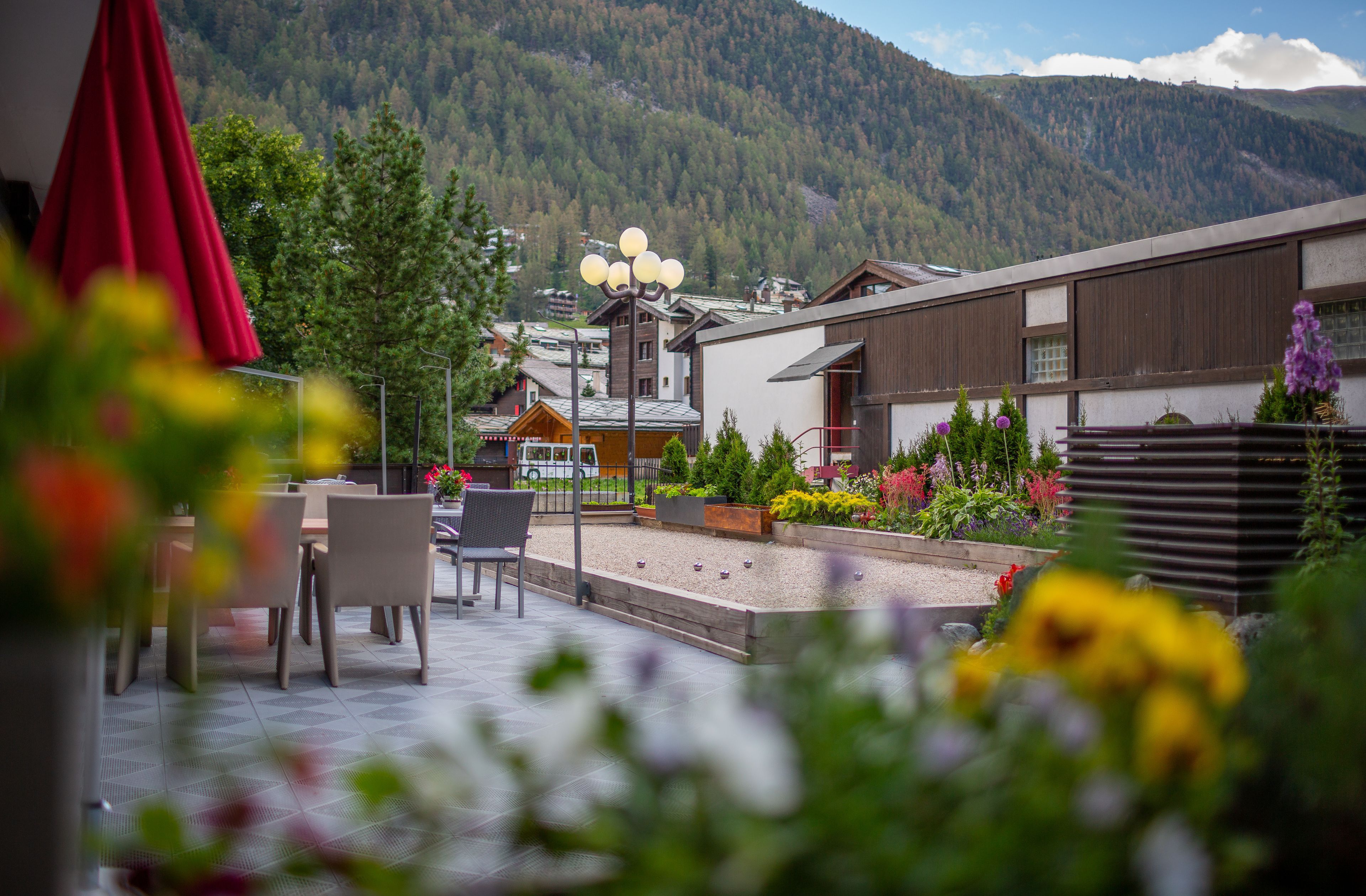 A patio area with outdoor seating, a red umbrella, and a mountain backdrop.