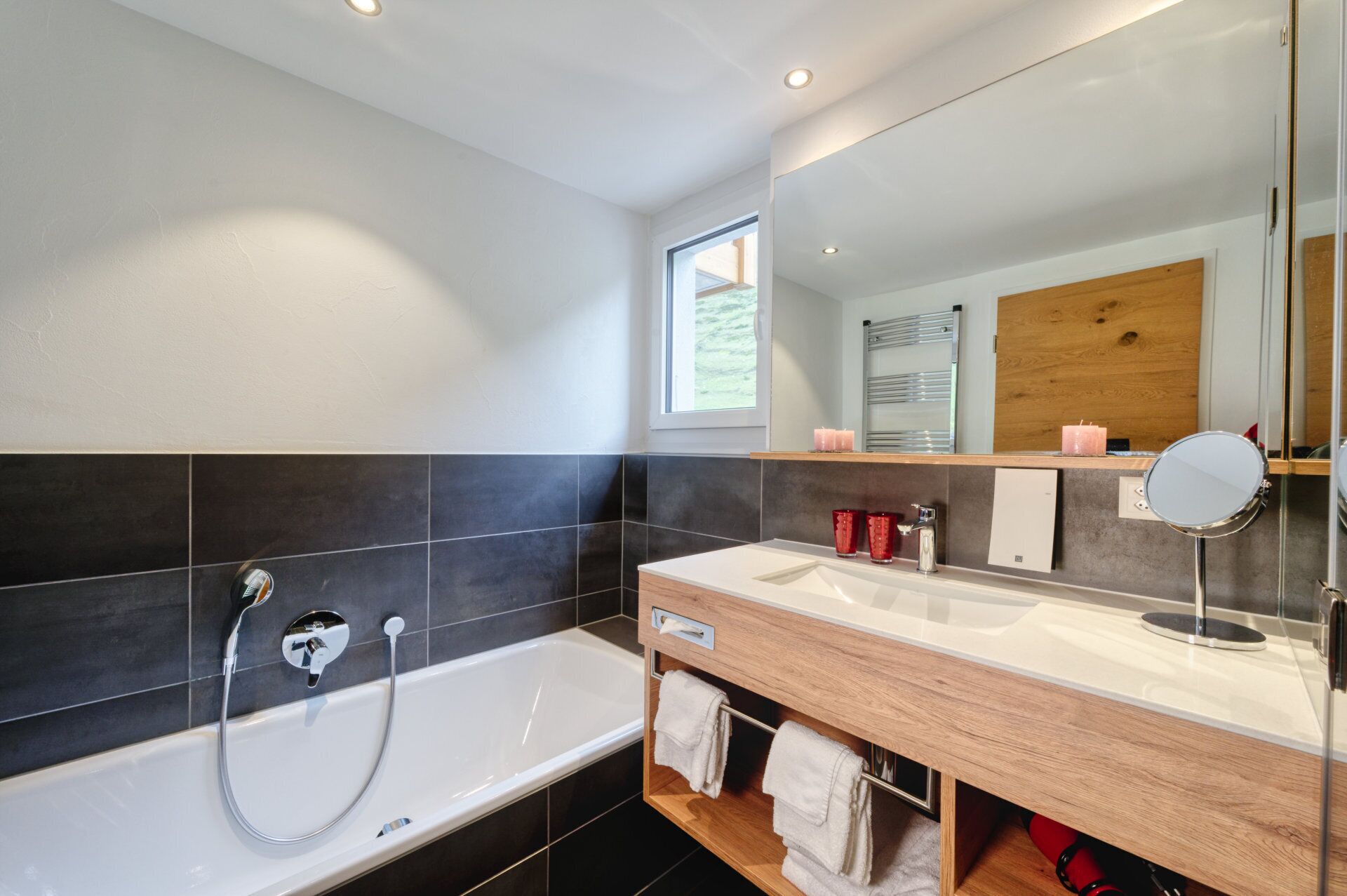 A modern bathroom with a bathtub, a vanity with a mirror, and a window providing natural light.