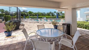 A covered outdoor seating area with a pool in the background. - San Marco Residence 604- Across the Street from Beach, Hotels, Restaurants and Shopping!  Sleeps 6! (Marco Island)